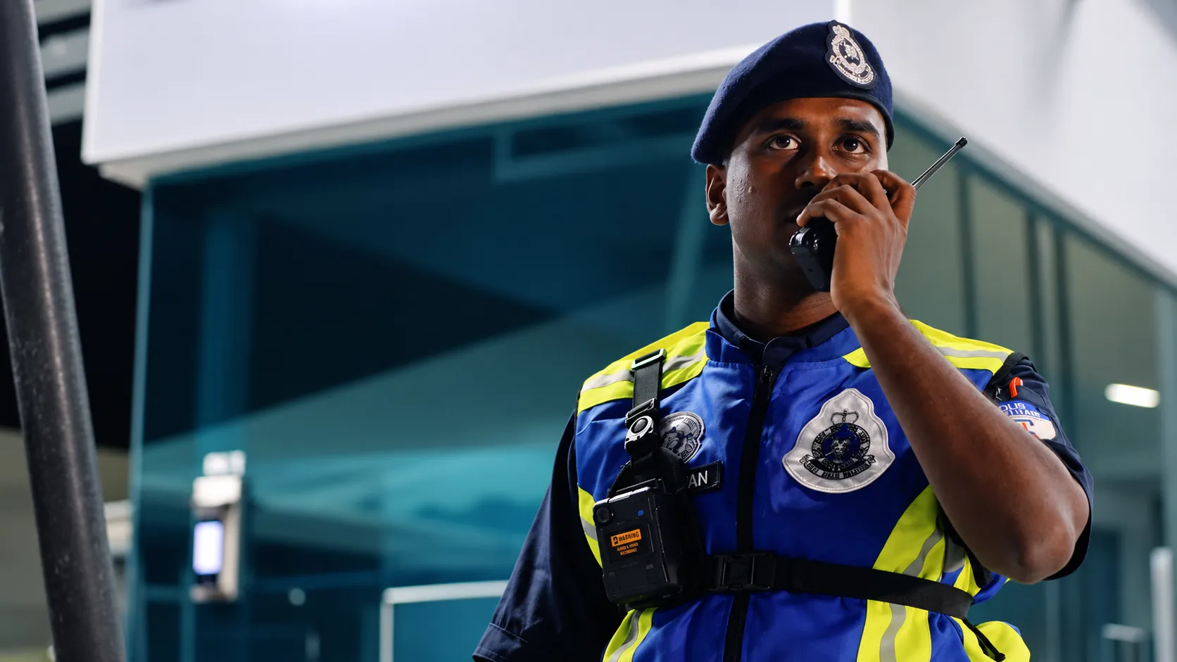 Campus security officer using two-way radio while wearing Motorola VB400 body-worn camera during night operations